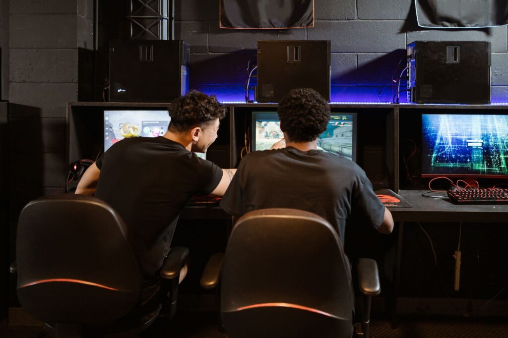 jL beats former team NAVI as Vitality reach PGL Masters Bucharest playoffs Two players seen from behind at gaming PCs with monitors in a dim esports room